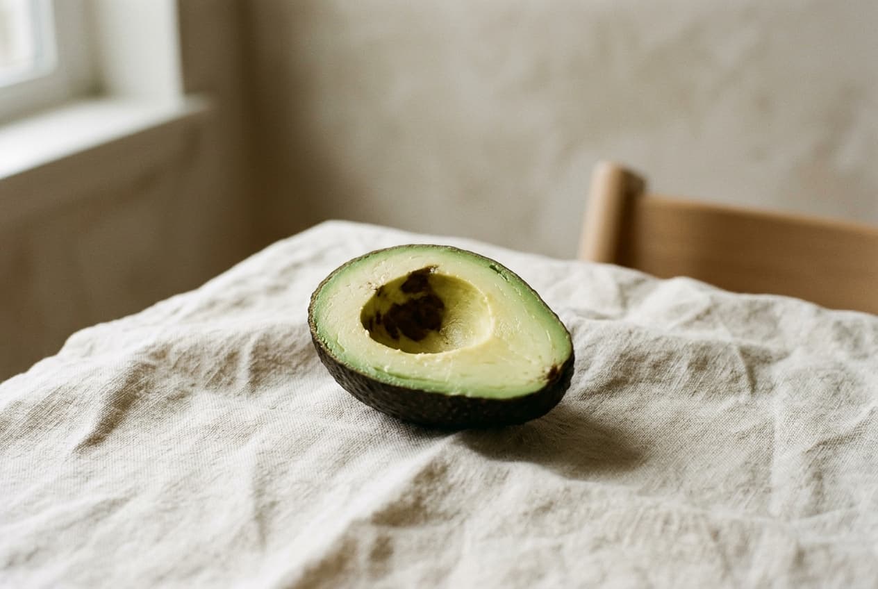 A single avocado half, cut side up, on a linen cloth